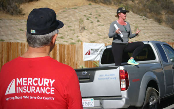 woman from habitat for humanity delivering speech in back of pickup truck