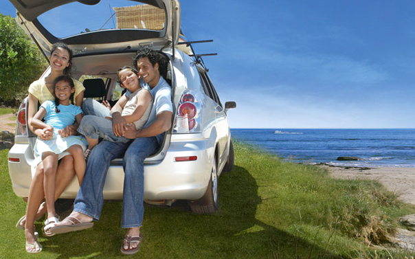 Family of four sitting in the back of a car on the beach