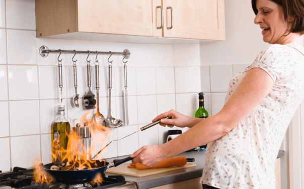 pan catches fire while woman cooks