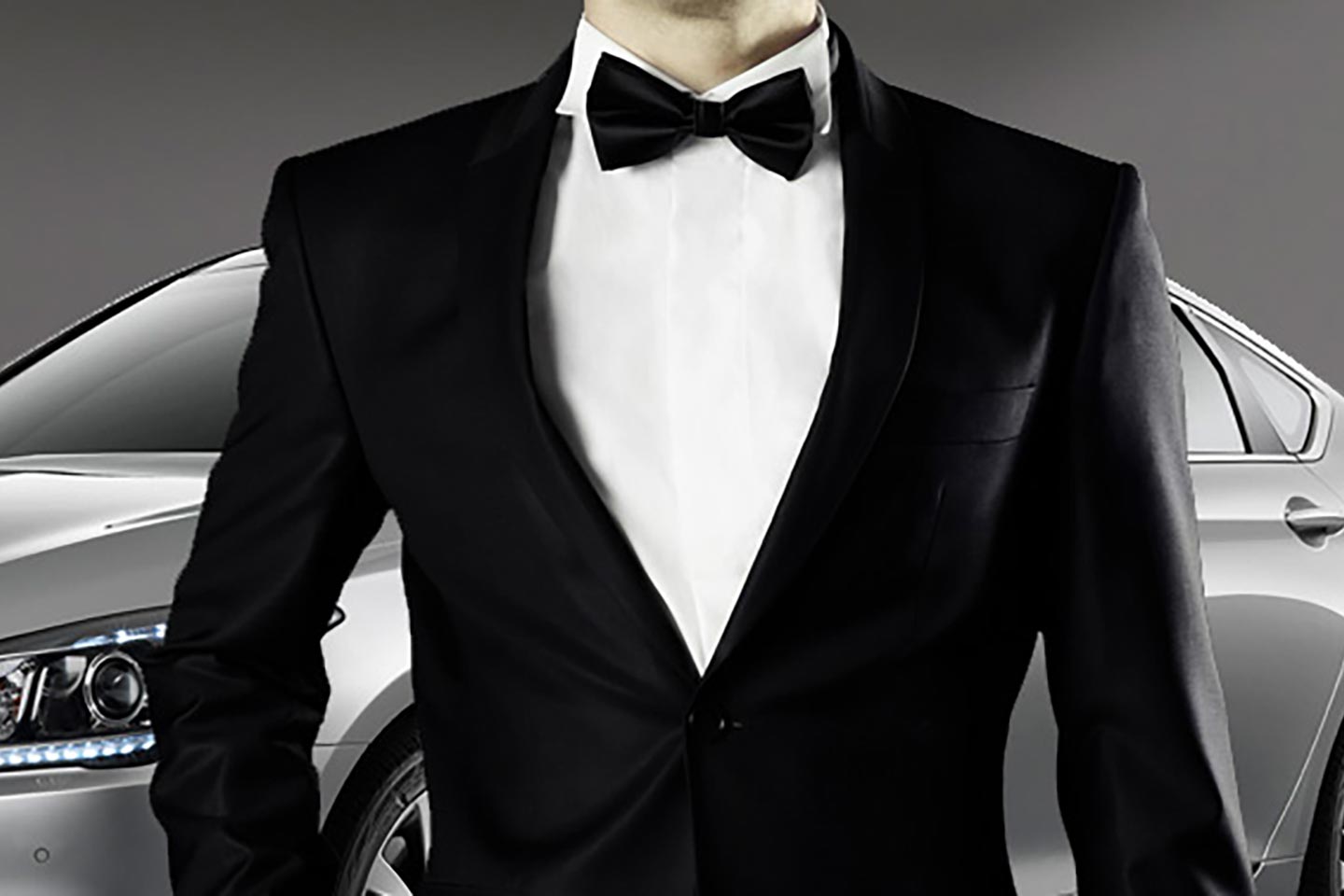 Man in tuxedo dressed as James Bond standing in front of car