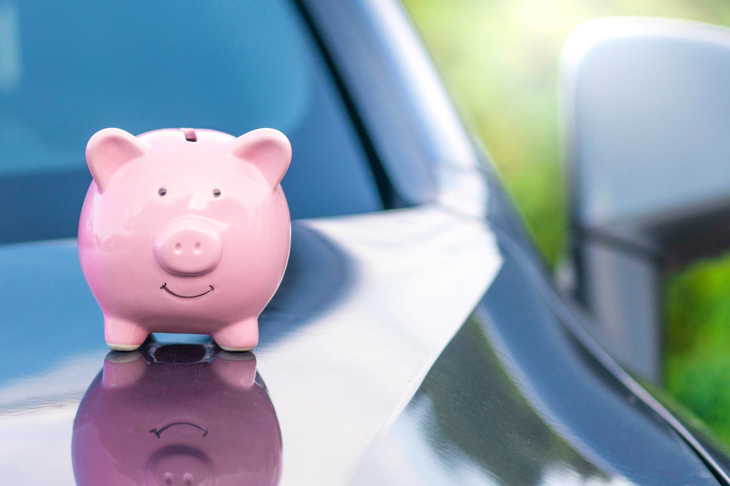 Piggy bank sitting on the hood of a car
