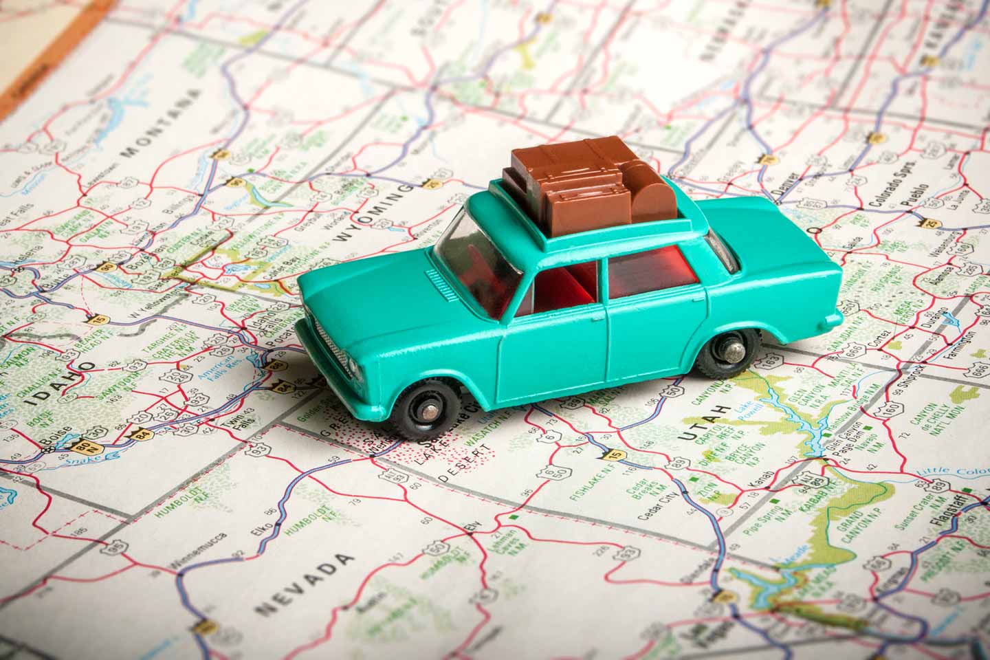 Vintage toy car with luggage on the roof with a road map of the U.S.