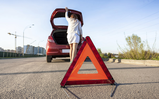 Woman  opening trunk and placing hazard sign by car