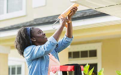 Woman caulking exterior of house