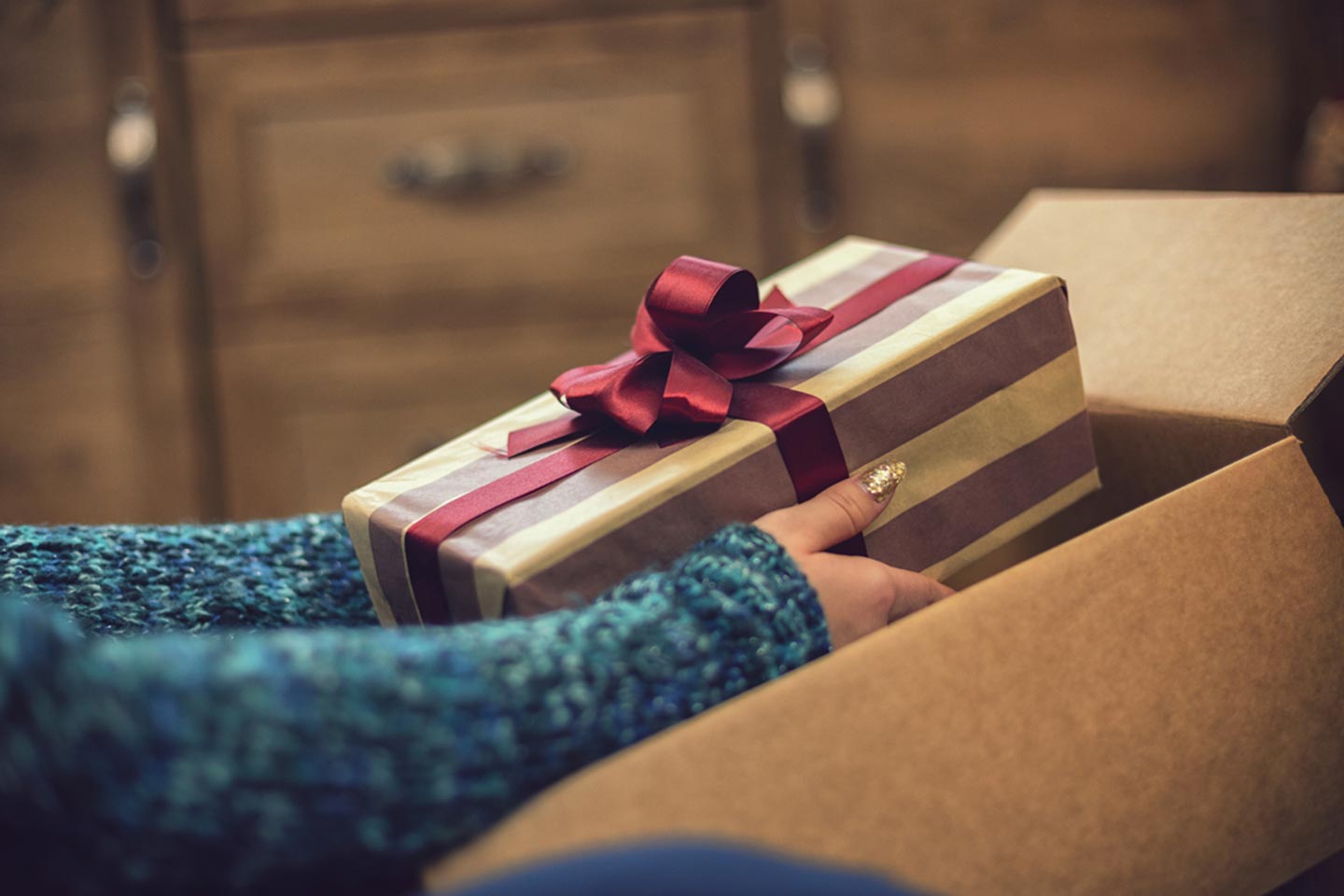 Woman taking a wrapped holiday present out of a box