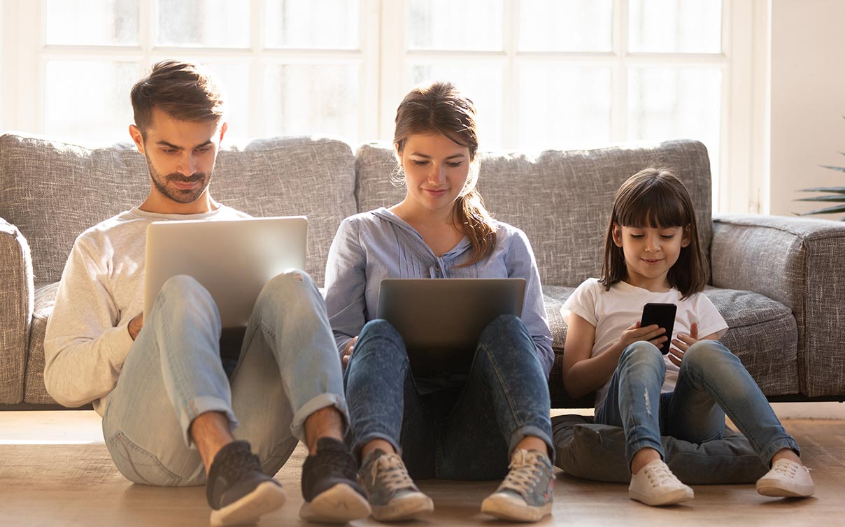 Children sitting together at home using different wireless devices