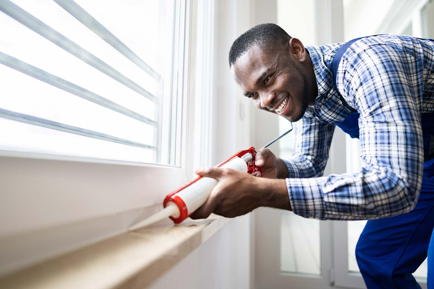 Homeowner applying a caulk sealant to window seal