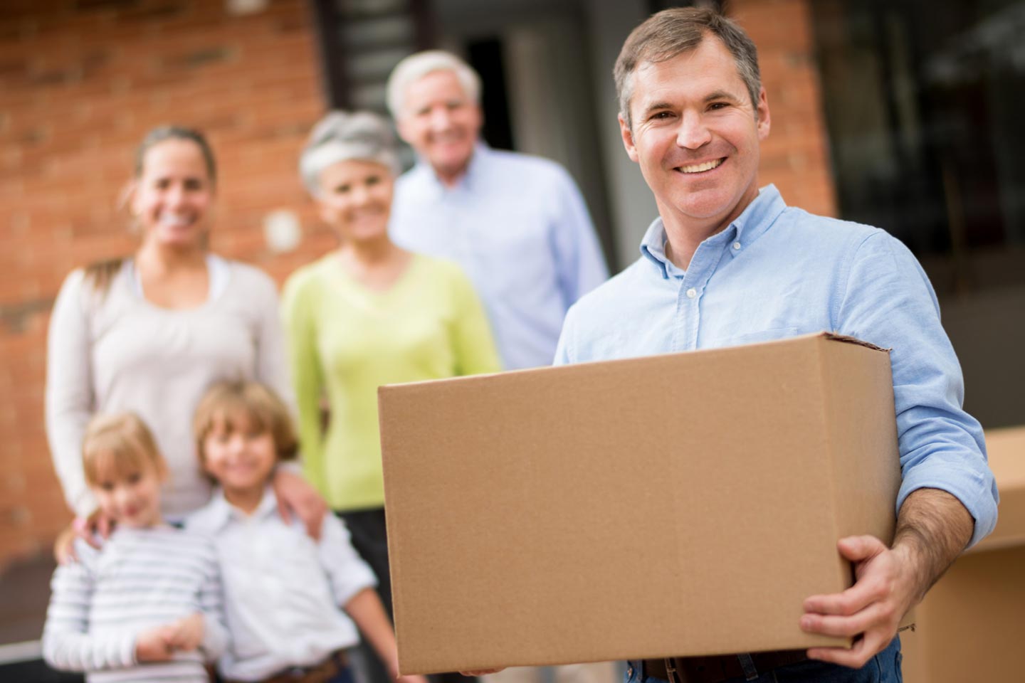 Man moving into a house with his family and holding a cardboard box