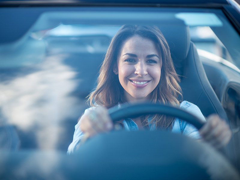 woman driving a convertible and smiling