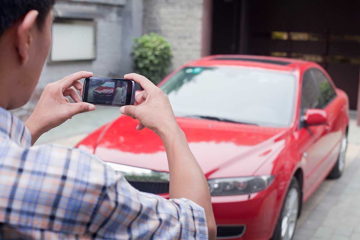 Agent taking photo of damage on front of car