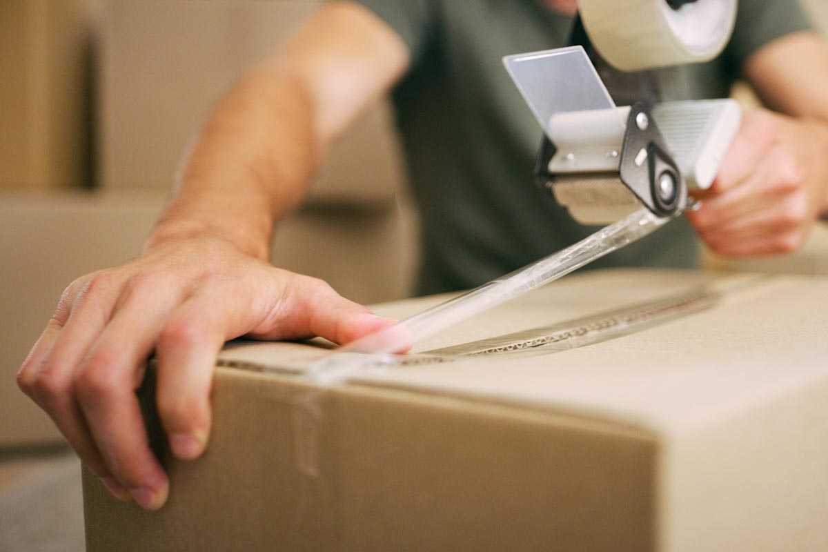 Man packing up a cardboard box with tape