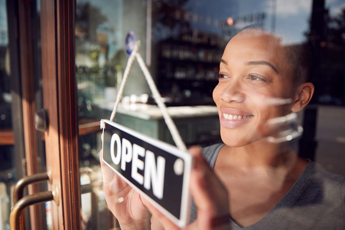 Owner of coffee shop turning round open sign on door