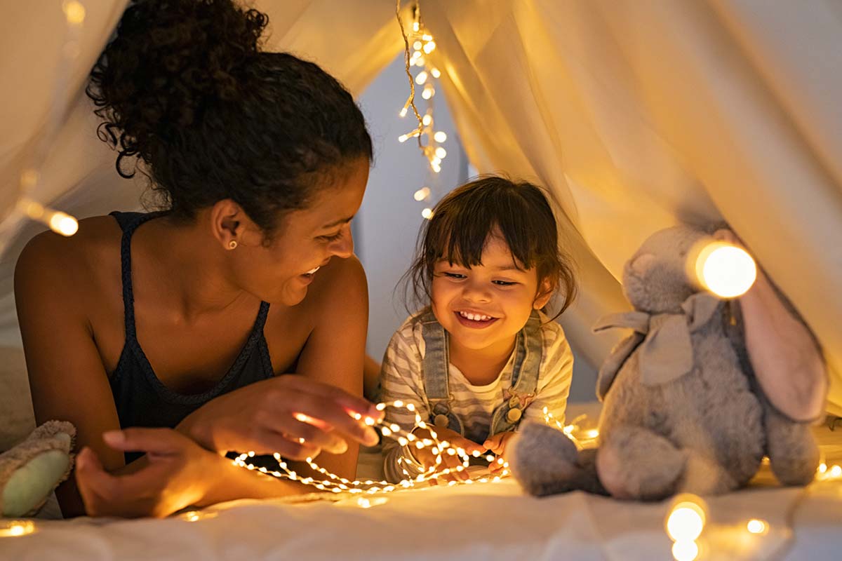 Mother and daughter playing at home in tent