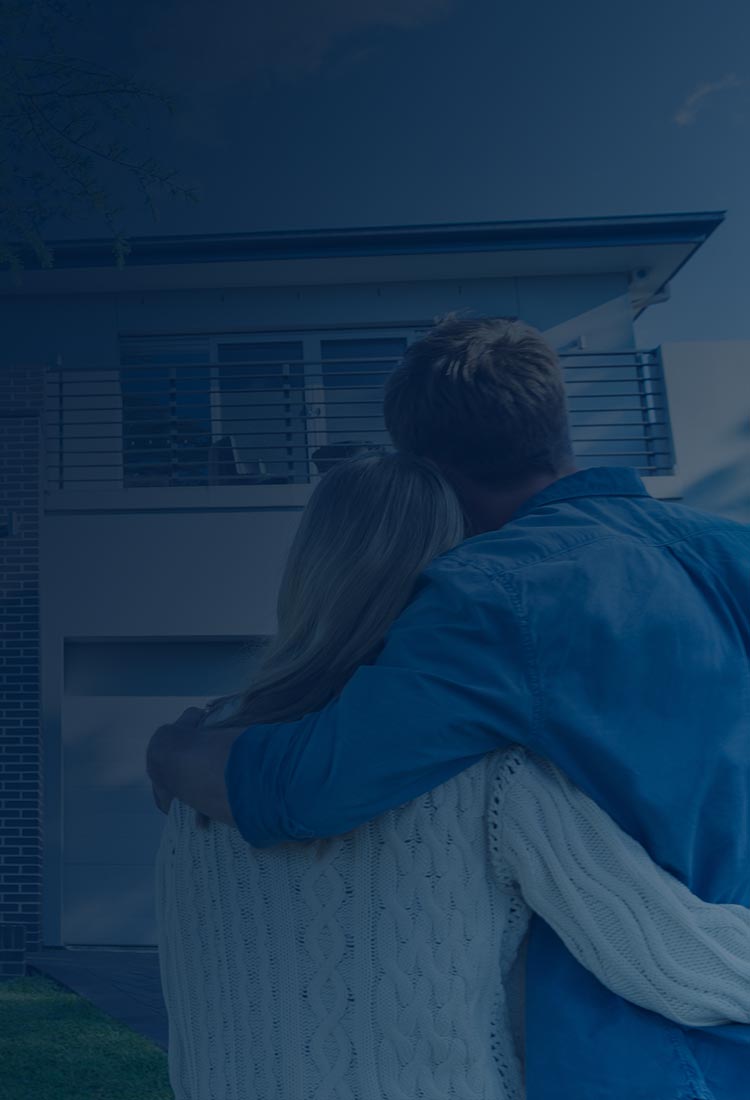 Happy couple hugging and looking at front of their house